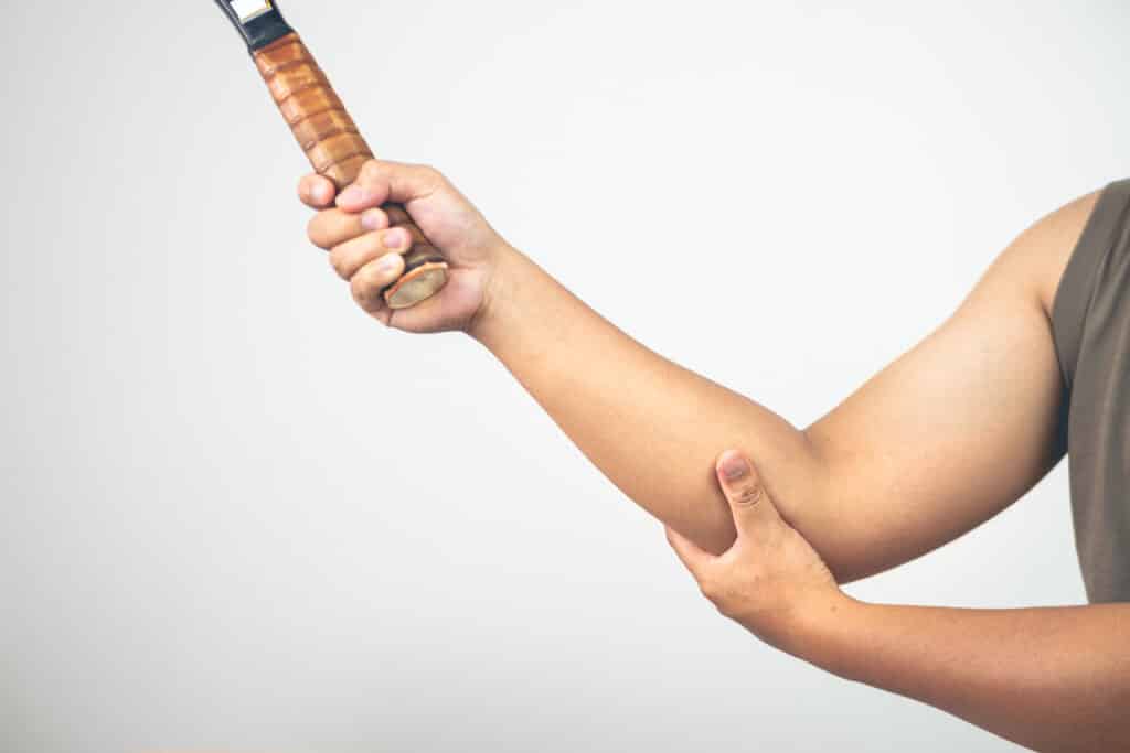 Homme qui tient son coude à cause d'une épicondylite